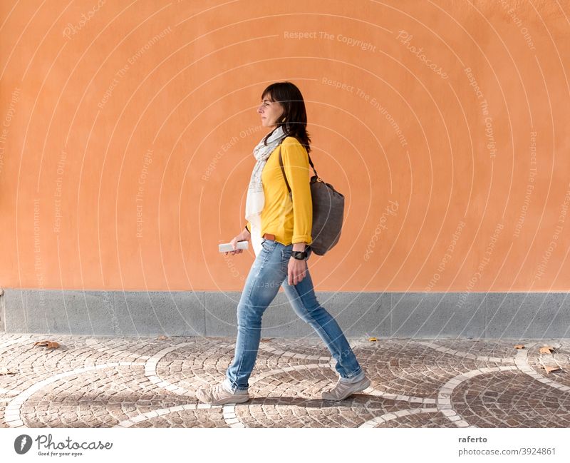 Seitenansicht eines Backpacker-Reisenden zu Fuß gegen orange Wand in der Stadt Frau laufen Rucksack Straße im Freien Großstadt Person urban 1 Reisender Urlauber