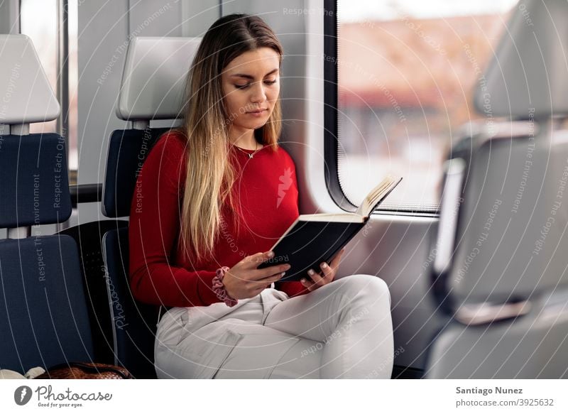 Mädchen liest Buch im Zug lesen fokussiert reisend Porträt jung 20s Vorderansicht blond hübsch Kaukasier Blick Frau Reisender Verkehr im Innenbereich