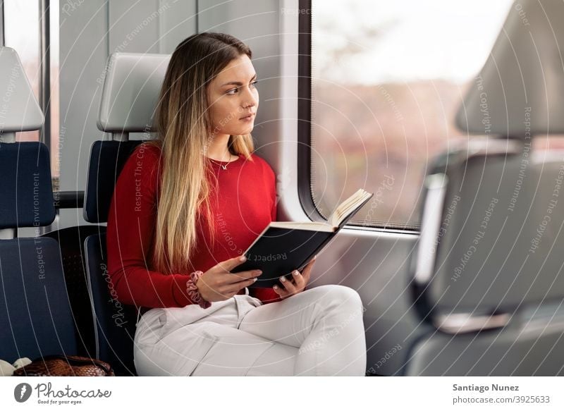 Mädchen liest Buch im Zug lesen fokussiert reisend Porträt jung 20s Vorderansicht blond hübsch Kaukasier Blick Frau Reisender Verkehr im Innenbereich
