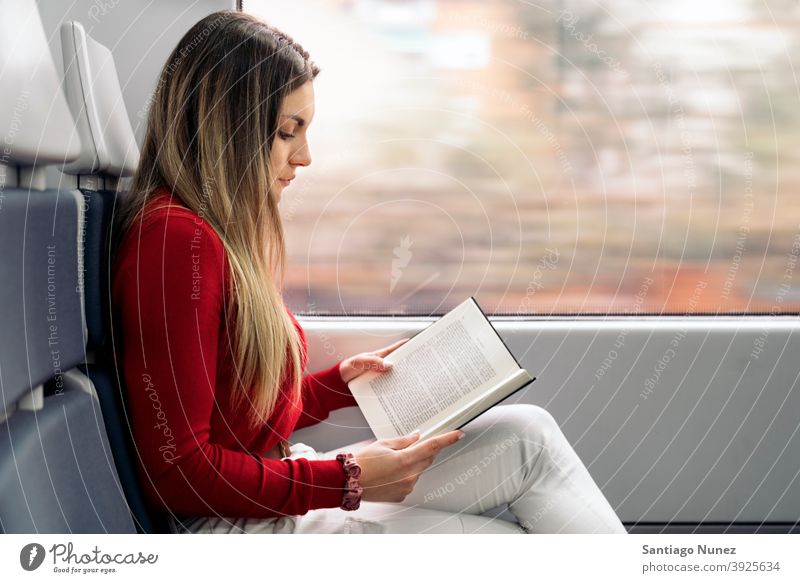 Mädchen liest Buch im Zug Seitenansicht lesen fokussiert reisend Porträt jung 20s blond hübsch Kaukasier Blick Frau Reisender Verkehr im Innenbereich