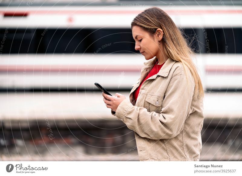 Blondes Mädchen wartet auf den Zug Seitenansicht Frau Kaukasier Bewegung Porträt per Telefon Tippen Blick Hintergrund Stehen außerhalb im Freien U-Bahn Verkehr