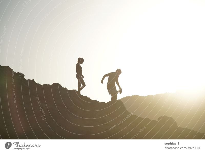 Silhouette von Paar zu Fuß bergab im Gegenlicht bei Sonnenuntergang Berge u. Gebirge Urlaub laufen Abenteuer Hintergrundbeleuchtung wandern Hügel Spaziergang