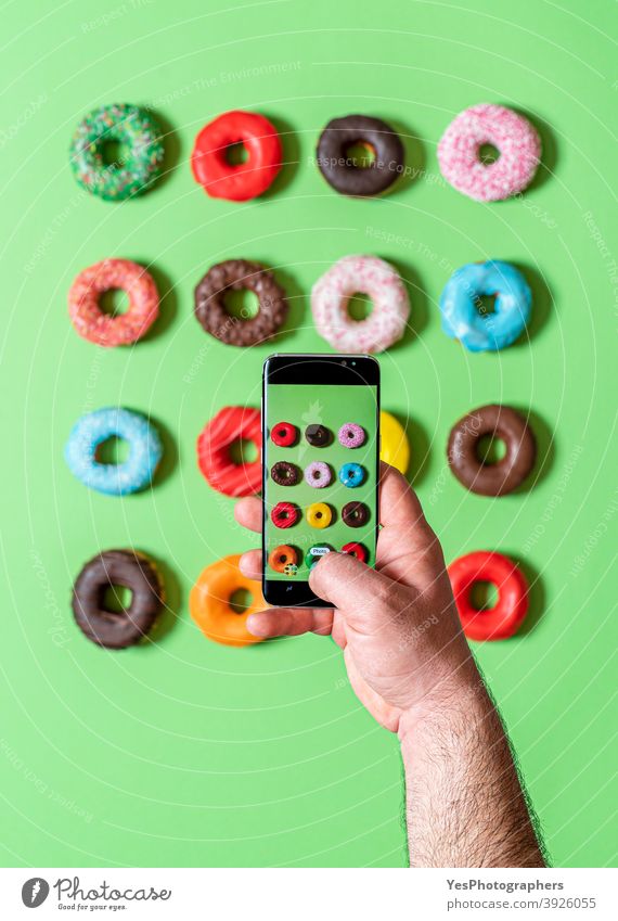 Aufnehmen von Fotos von Donuts mit dem Smartphone. Fotografieren von Lebensmitteln in der Draufsicht. obere Ansicht ausgerichtet sortiert Hintergrund gebacken