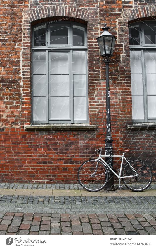 Weißes Fahrrad an eine Straßenlaterne vor einer Backsteinmauer gebunden Hintergrund retro Wand altehrwürdig Architektur Baustein Europa Europäer Fassade