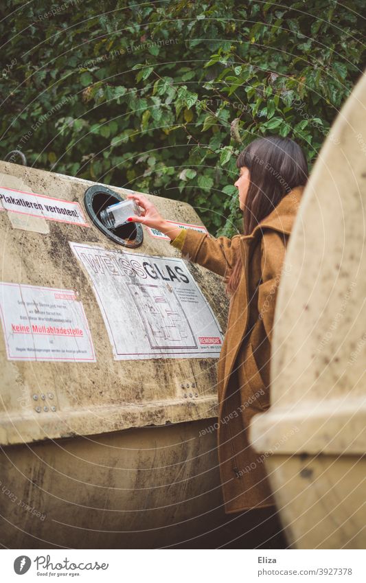 Eine junge Frau entsorgt eine Flasche im Altglascontainer. Recycling. Container Flaschen Glasabfall Müll Müllbehälter Mülltrennung Müllentsorgung entsorgen