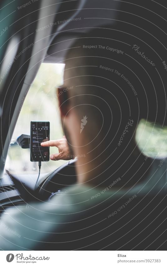 Mann sitzt im Auto und tipp etwas in sein Handy tippen Navigation Halterung Handyhalterung Mobiltelefon Smartphone Autofahren während Fahrer Autofahrer Verkehr