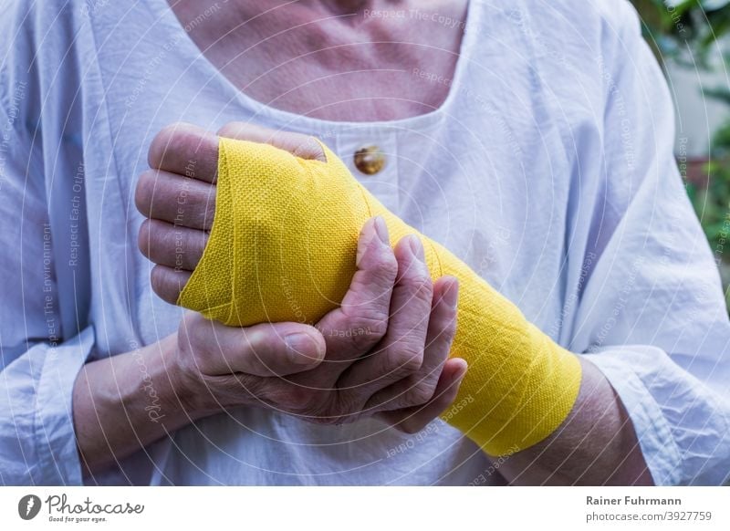 Eine Frau hat eine Verletzung am Handgelenk, sie trägt einen gelben Verband Gesundheit Krankheit Arbeitsunfall Arbeitsausfall Krankenversicherung Person