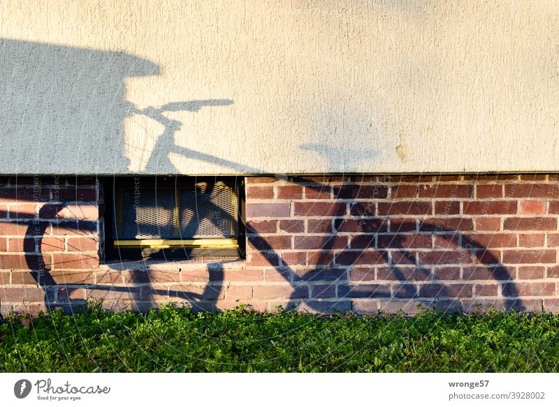 Schattenbild eines im Radständer stehenden Fahrrades auf der Wand eines Mehrfamilienhauses Schattenspiel Schattenwurf Mountainbike MTB Hauswand Fassade
