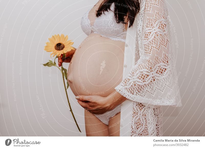 Schwangere Frau hält eine Blume Unterleib Baby Hintergrund schön Schönheit Bauch Körper Blumenstrauß Textfreiraum erwartungsvoll Familie Fröhlichkeit Gesundheit