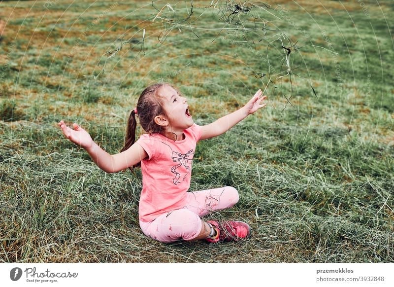 Kleines Mädchen spielt mit Gras genießen Sommertag spielen auf dem Feld während der Ferien Reise Glück Aufregung Genuss Freizeit Urlaub Ausflug Spielen Emotion