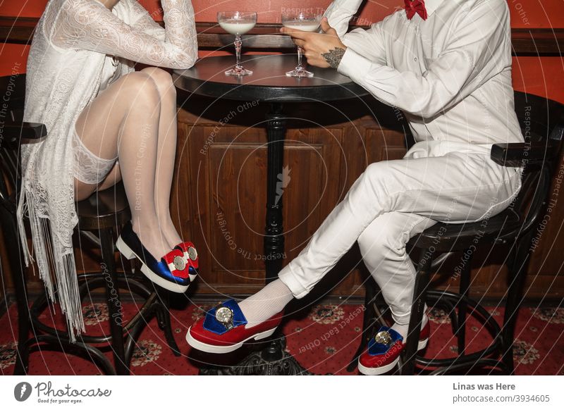 Es ist ein Date und die beiden jungen Leute flirten über den ganzen Tisch. Ganz in Weiß gekleidet und mit avantgardistischen Schuhen, die schon von weitem glänzen, trinken sie ein Glas Milch. Der rote Teppich repräsentiert dieses schicke Restaurant als perfekten Ort zum Flirten.