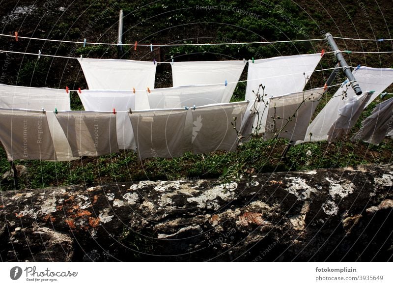 Blick über die Mauer auf Wäscheleinen mit weißen Laken Wäsche waschen Waschtag Haushalt Häusliches Leben Sauberkeit Haushaltsführung Alltagsfotografie trocknen