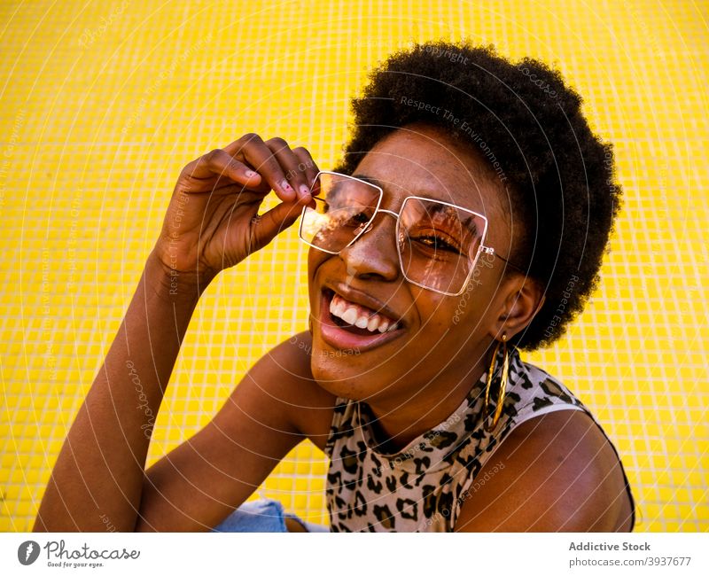 Lachende schwarze Hipster-Frau mit stylischer Sonnenbrille Stil trendy heiter Afro-Look modern jung Afroamerikaner ethnisch Optimist Brille Accessoire Design