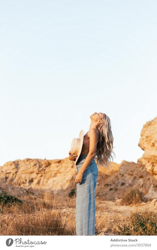 Nackte Frau bedeckt Brust mit Hut in der Natur schlank Deckung oben ohne ruhig genießen Sonnenuntergang Stil Jeanshose sich[Akk] entspannen Harmonie stehen