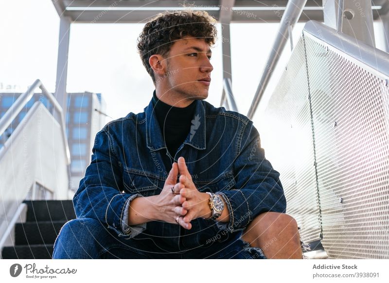 Stilvoller Mann sitzt auf einer Treppe in der Stadt Jeansstoff Outfit modern Großstadt trendy Model ernst männlich Treppenhaus Straße Schritt urban sitzen