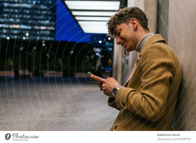 Fröhlicher Mann mit Smartphone auf der Straße Nachricht soziale Netzwerke heiter Großstadt Abend Browsen Lächeln unterhalten männlich Gebäude gutaussehend
