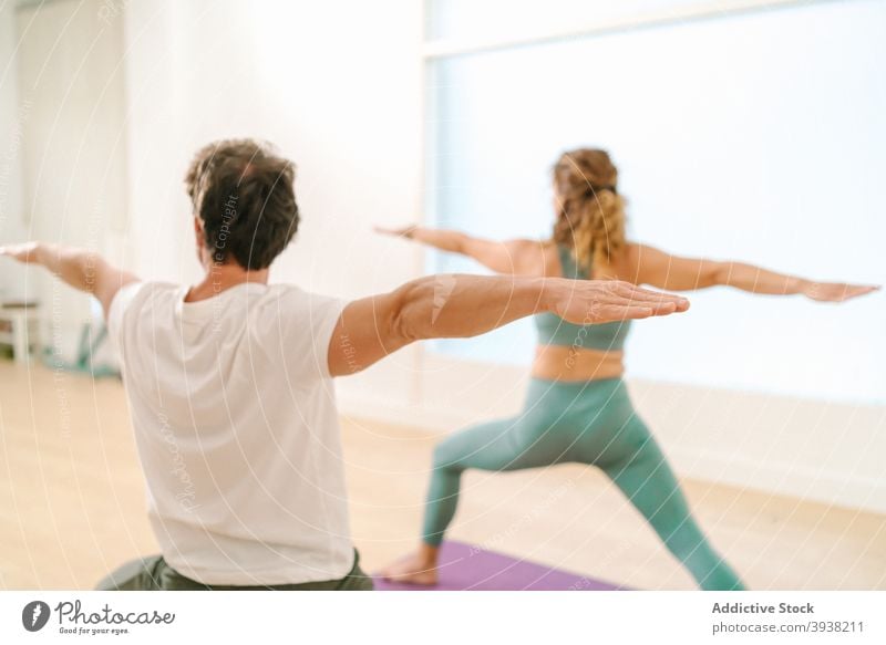 Mann und Frau tun Yoga in Warrior Pose im Studio Krieger-Pose üben Gleichgewicht Zusammensein Klasse Zen Barfuß ausdehnen Arme Atelier beweglich Asana Wellness