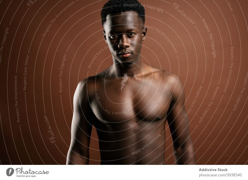 Stilvoller schwarzer Mann mit nacktem Oberkörper im Studio nackter Torso Jeanshose trendy Model muskulös ohne Hemd selbstbewusst männlich ethnisch