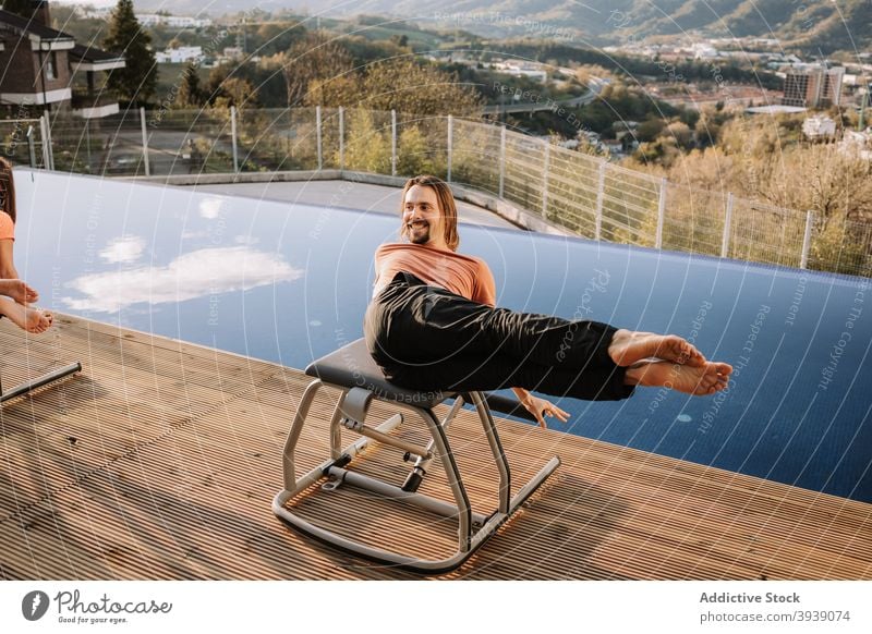 Fröhlich Mann tun abs Übung auf Pilates Stuhl Bauchmuskeln Unterleib Training Sportbekleidung Terrasse heiter männlich physisch Wohlbefinden Fitness Wellness