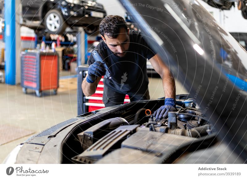Techniker überprüft Auto im modernen Service untersuchen PKW Mechaniker Mann Dienst Taschenlampe Fackel Automobil Fahrzeug Reparatur Beruf männlich Verkehr