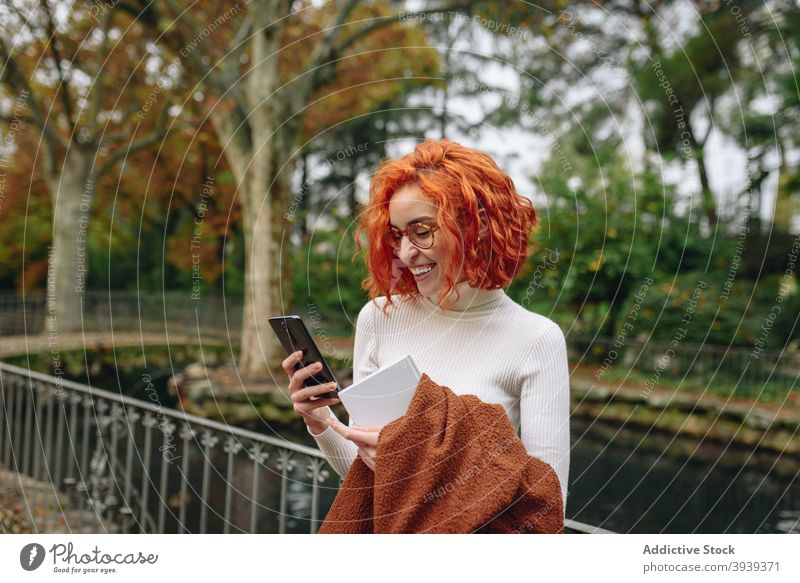 Friedliche rothaarige Frau, die im Park auf ihrem Smartphone surft Browsen Rotschopf Vorschein App Talkrunde soziale Netzwerke Internet rote Haare Surfen online