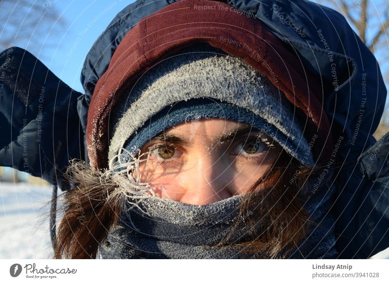 Frau, die aus mehreren Schichten von Winterkleidung herausschaut Auge Frost kalt Einfrieren Schnee