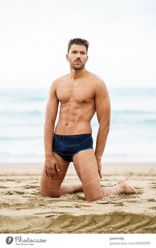 Hübscher Mann auf den Knien auf dem Sand des Strandes sexy männlich muskulös gutaussehend Gesundheit Wasser Menschen passen MEER Model Bauchmuskeln Urlaub