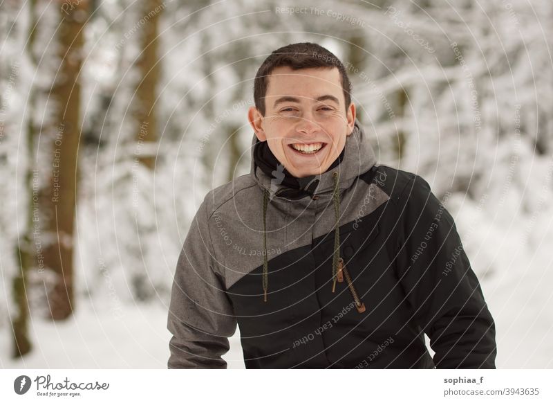 Winter - glücklicher junger Mann hat Spaß im Schnee und lacht, lächelt in die Kamera Porträt Lächeln Lachen Teenager Fröhlichkeit Glück Freude Junge Typ kalt