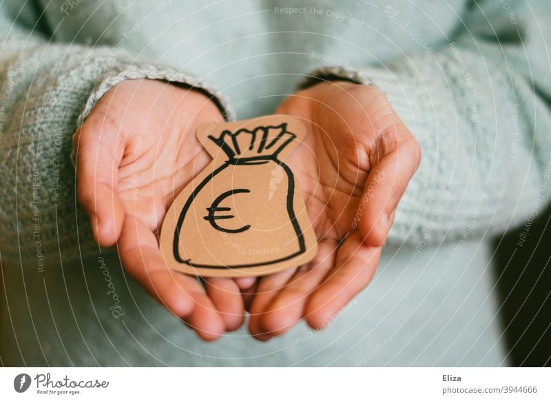 Eine Person hält einen gemalten Geldsack in den Händen. Konzept Geldgeber und Spende. geben bekommen Finanzen Investition sparen Erspartes Euro Reichtum