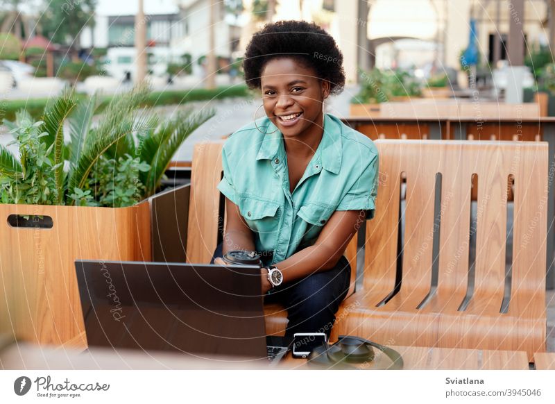 Porträt eines jungen afrikanischen Mädchens, das in einem Café während einer Kaffeepause an einem Laptop arbeitet. Eine Pause, entspannen, online arbeiten, freiberuflich