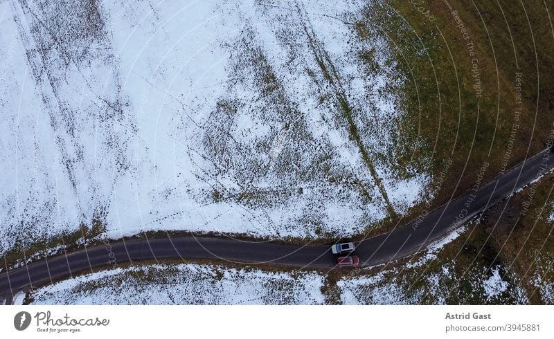 Drohnenfoto von zwei Autos die im Winter auf einer engen Straße aneinander vorbeifahren luftaufnahme drohnenfoto auto winter straße schnee sonne schatten licht