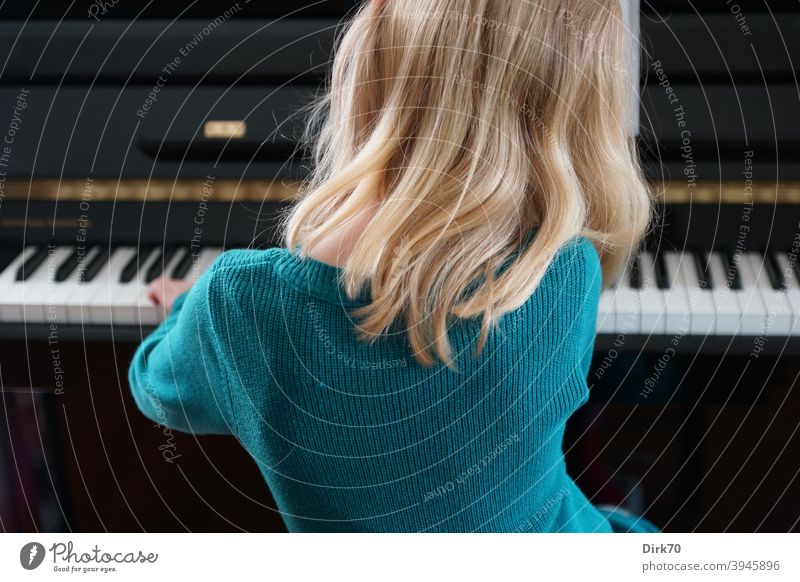 Kleine Pianistin - Rückansicht eines blonden Mädchens beim Klavierspiel Kind Kindheit Musik Musikerin Klavierspielen klavierspielerin Klaviatur Innenaufnahme