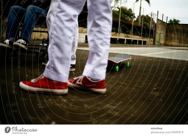 ein Junge im Rollstuhl mit Skateboarder Freunde spielen in Tennisplatz Freizeit Lebensbilanz Subkultur Hintergrund Textfreiraum echte Menschen Gerät Schiffsdeck