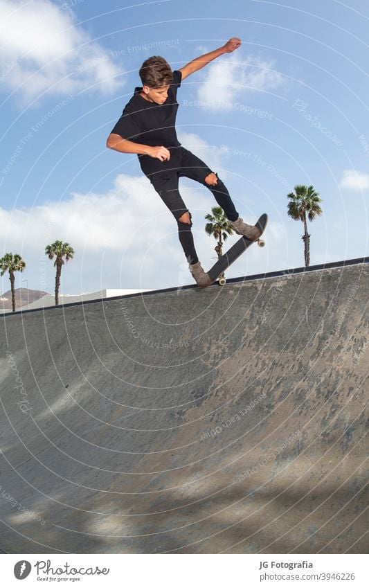 Junger Skateboarder führt Tricks in einem Park aus, mit Straßenhintergrund und blauem Himmel. jung springen Großstadt Lifestyle Stunt männlich Aktion aktiv Spaß