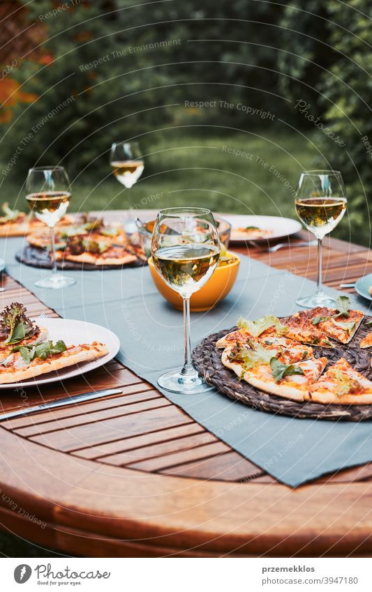 Abendessen in einem Hausgarten. Pizza, Salate, Früchte und Weißwein auf dem Tisch in einem Hinterhof Getränk Feier Speise trinken Essen Festessen Lebensmittel