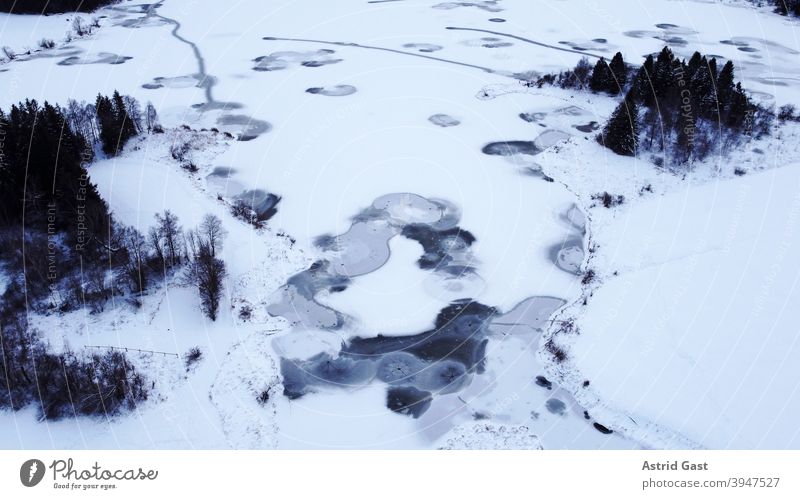Luftaufnahme mit einer Drohne von einem zugefrorenen See in Bayern luftaufnahme drohnenfoto see gewässer eis winter schnee wasser kreise formen eisschicht