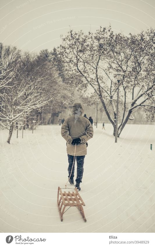 Ein Mann zieht einen Schlitten durch den Schnee. Winterstimmung. ziehen Landschaft Holzschlitten Winterlandschaft Schneelandschaft kalt draußen Natur Bäume