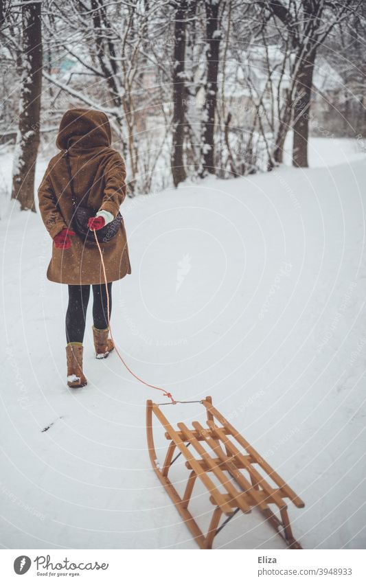 Eine Frau zieht einen Schlitten durch den Schnee. Winterstimmung. ziehen Landschaft Holzschlitten Winterlandschaft Schneelandschaft kalt draußen Natur Bäume