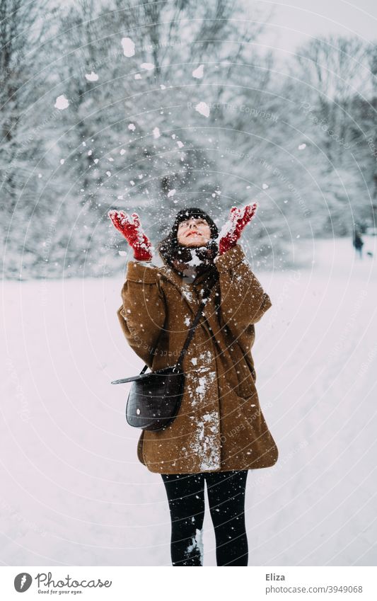 Frau wirft mit Schnee im Winter werfen Freude Schneelandschaft verschneit Natur draußen kalt weiß Winterstimmung Winterwald Wintertag Handschuhe Mantel jung
