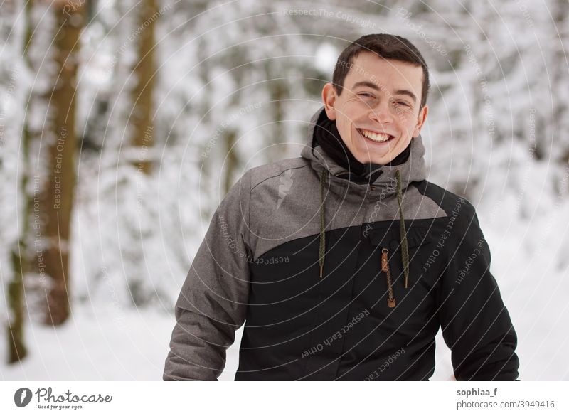 Winter - glücklicher junger Mann hat Spaß im Schnee und lacht, lächelt in die Kamera Porträt Lächeln Lachen Teenager Fröhlichkeit Glück Freude Junge Typ kalt