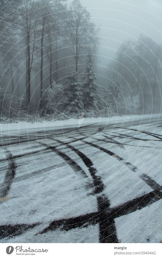 ein winterlicher Wald mit Reifenspuren auf einer glatten Straße mit Schnee und Eis Winter Glatteis Eis und Schnee Eis und Frost Spuren Bäume Natur Landschaft