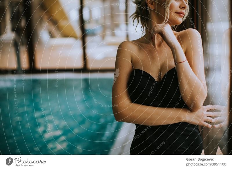 Schöne junge Frau steht am Fenster am Schwimmbad Erwachsener attraktiv schön Schönheit blau Körper Kaukasier niedlich Tag Fitness im Innenbereich Freizeit