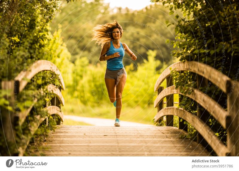 Schlanke Frau läuft entlang Holzweg im Park Sportlerin laufen Läufer Training schlank Athlet Herz aktiv Sommer salburua Vitoria Gasteiz Spanien Sportbekleidung