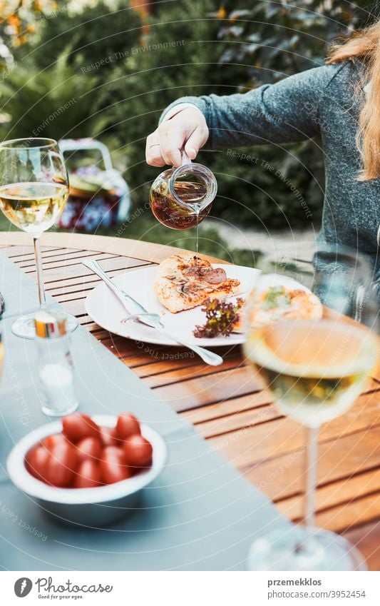 Familie und Freunde mit Mahlzeit - Pizza, Salate, Früchte und trinken Weißwein während Sommer-Picknick im Freien Abendessen in einem Haus Garten Hinterhof