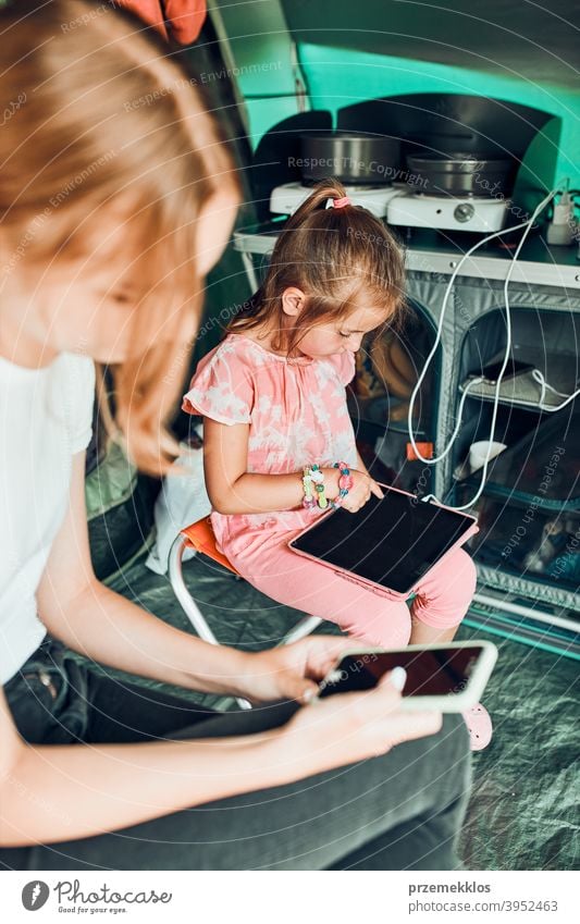 Schwestern verbringen Zeit in einem Zelt auf dem Campingplatz. Kinder mit Tablet spielen Spiele online während der Sommerferien Spielen Mädchen Geschwister