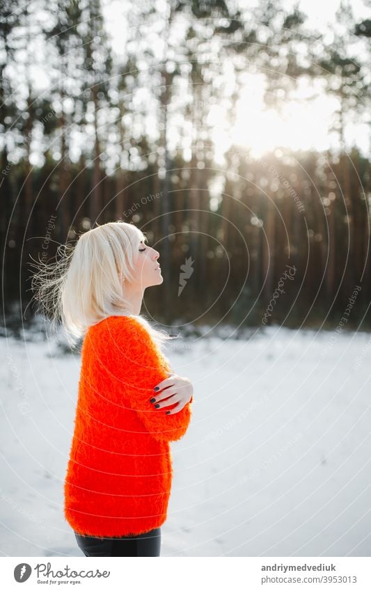Niedliche Mädchen haben Spaß in der gefrorenen Park. Frau in einem gestrickten Pullover.die Hände des Mädchens gefroren Winter Porträt im Freien orange Natur