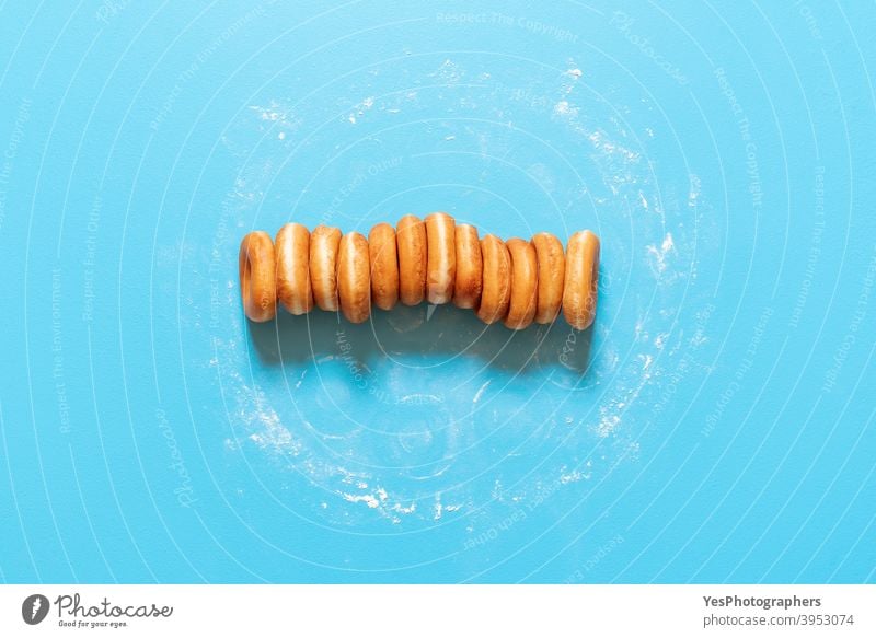 Donuts in einer Reihe auf blauem Hintergrund. Hausgemachte Ringkrapfen, Ansicht von oben ausgerichtet Amerikaner gebacken Bäckerei Blauer Hintergrund Frühstück