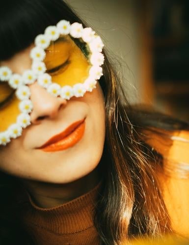 Frau mit Blümchen-Sonnenbrille im Sonnenlicht. Retrostimmung, Optimismus, gute Laune und Sommer. Sommerstimmung Frühling Sonnenschein farbenfroh gelb orange