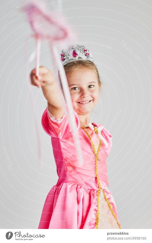Kleines Mädchen genießt ihre Rolle der Prinzessin. Adorable niedlichen 5-6 Jahre altes Mädchen trägt rosa Prinzessin Kleid und Tiara hält Zauberstab Fee Kind