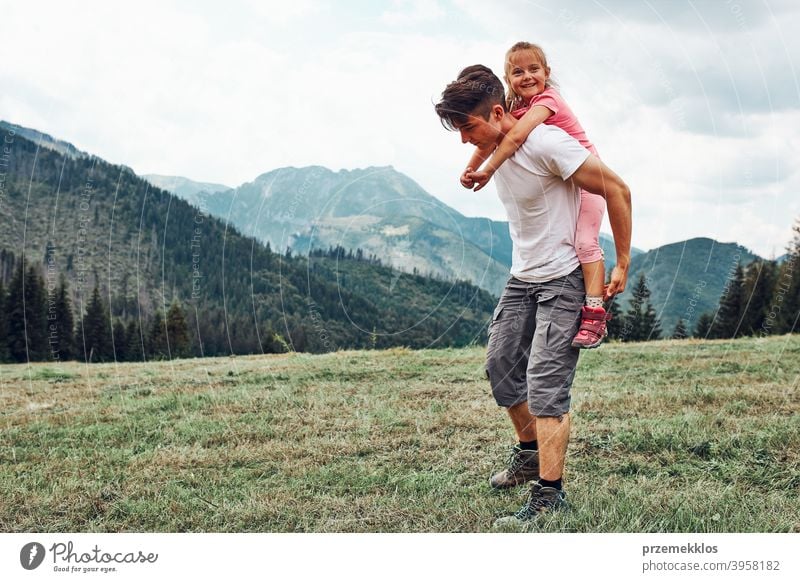 Junger Mann hält kleines Mädchen auf seinem Rücken. Kind spielt mit ihrem älteren Bruder reiten auf seinem Rücken genießen Sommertag zusammen Glück Aufregung